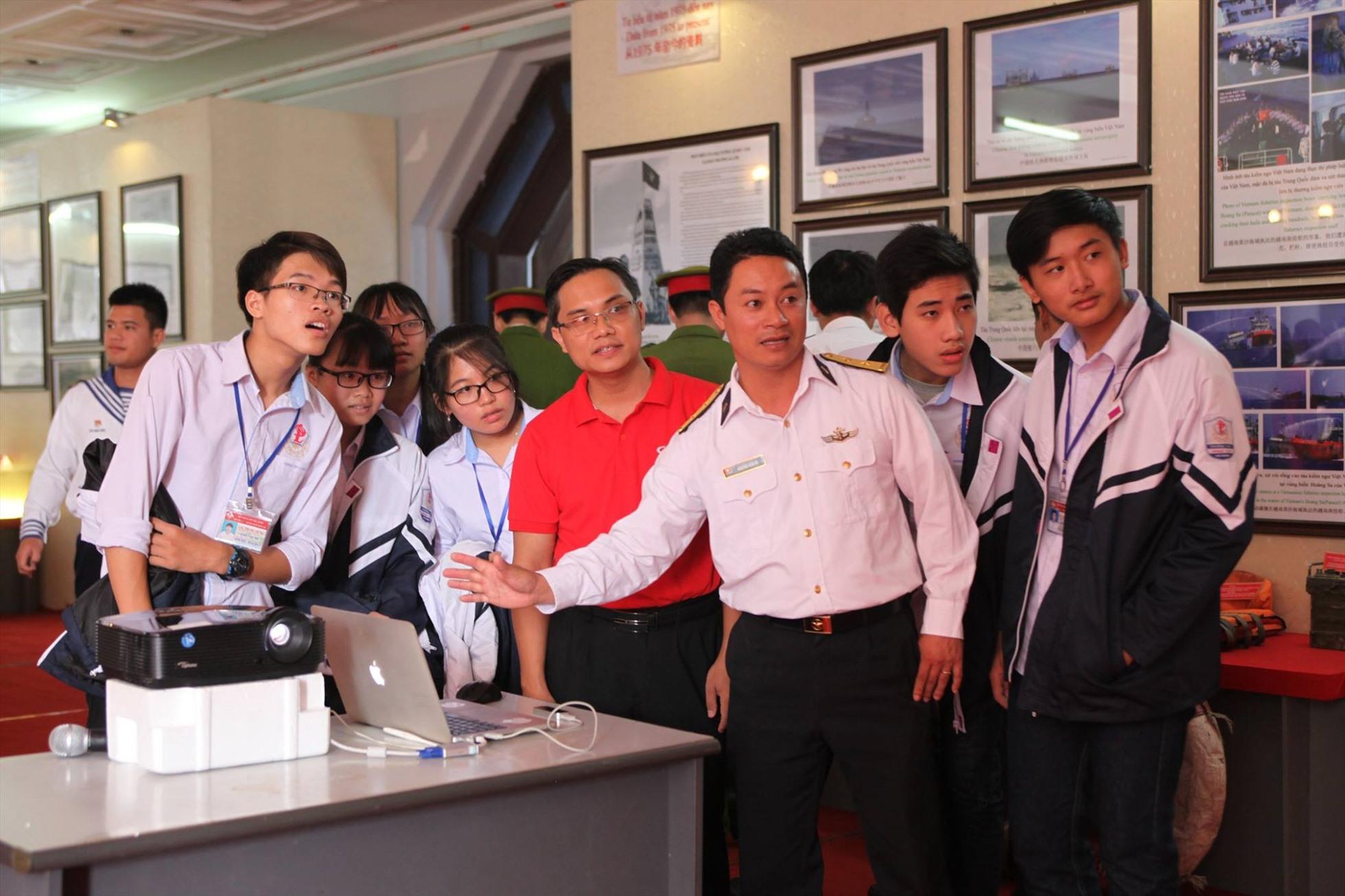 TS Cao Minh Thắng (áo đỏ) hướng dẫn trải nghiệm công nghệ thực tế ảo tại Triển lãm trưng bày tư liệu Chủ quyền biển đảo Việt Nam. Ảnh: Nhân vật cung cấp