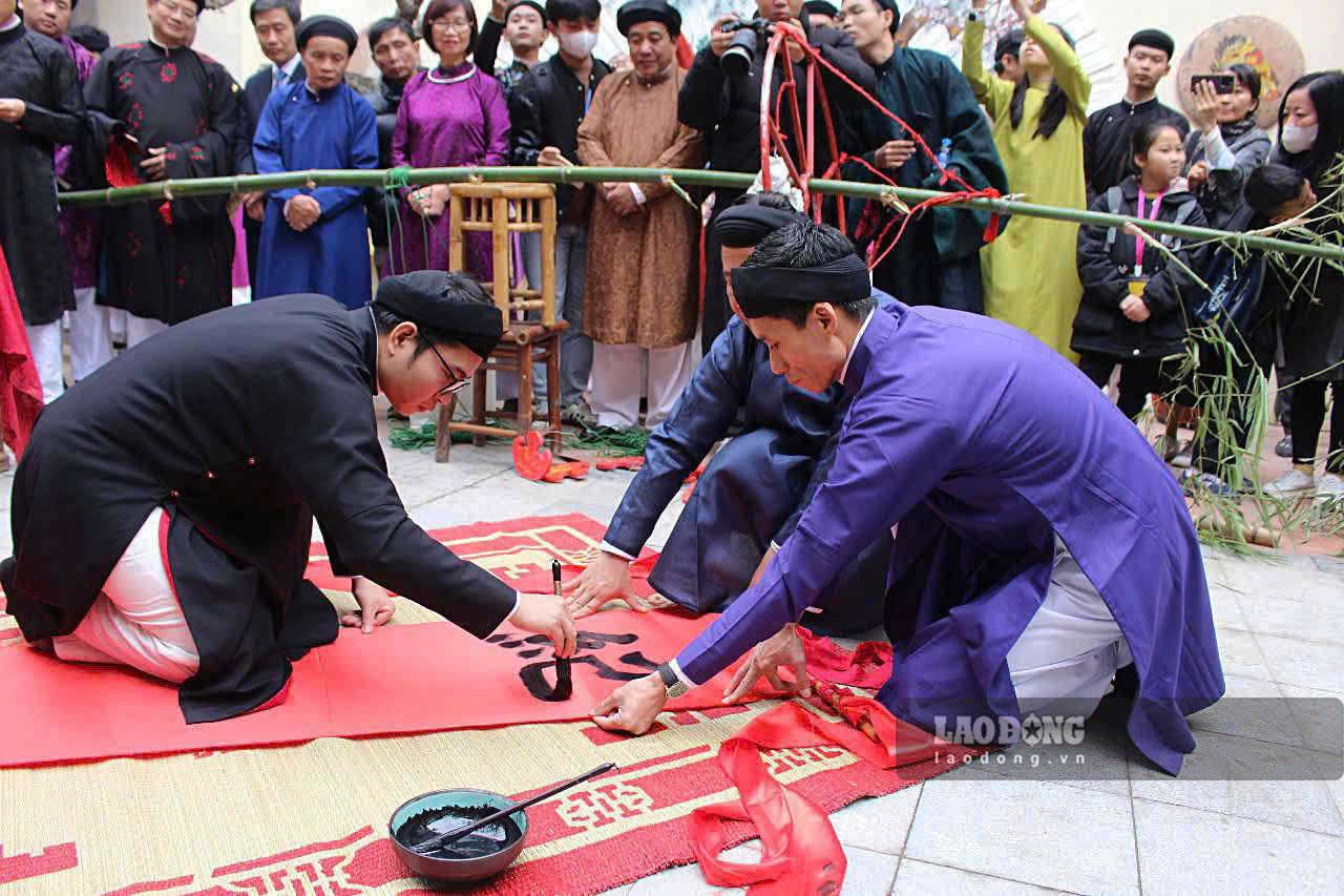 Lễ dựng cây nêu tại di tích đình Kim Ngân trong chương trình “Tết Việt - Tết Phố 2025”. Trước khi bắt đầu làm lễ dựng cây nêu, câu đối sẽ được viết để treo lên. Bốn chữ được viết bằng chữ Hán Nôm năm nay là “Kỷ nguyên vươn mình”. Ảnh: Thạch Lựu