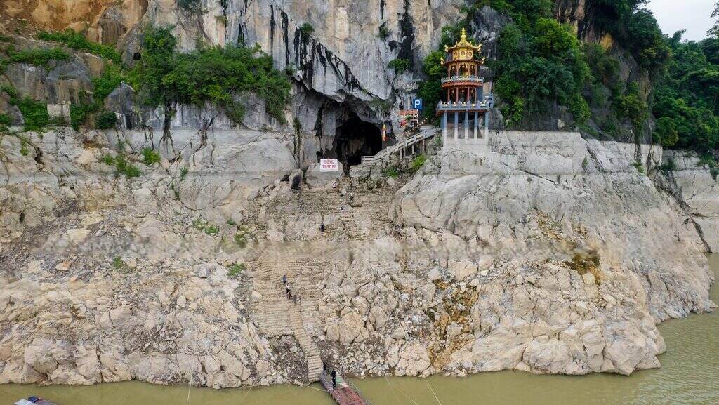 Lối lên đền Thác Bờ lộ rõ nền đá và bậc thang dài do mực nước sông Đà xuống thấp, có nơi rút sâu khoảng 40m – mức thấp kỷ lục trong nhiều năm qua. Ảnh: Alibaba