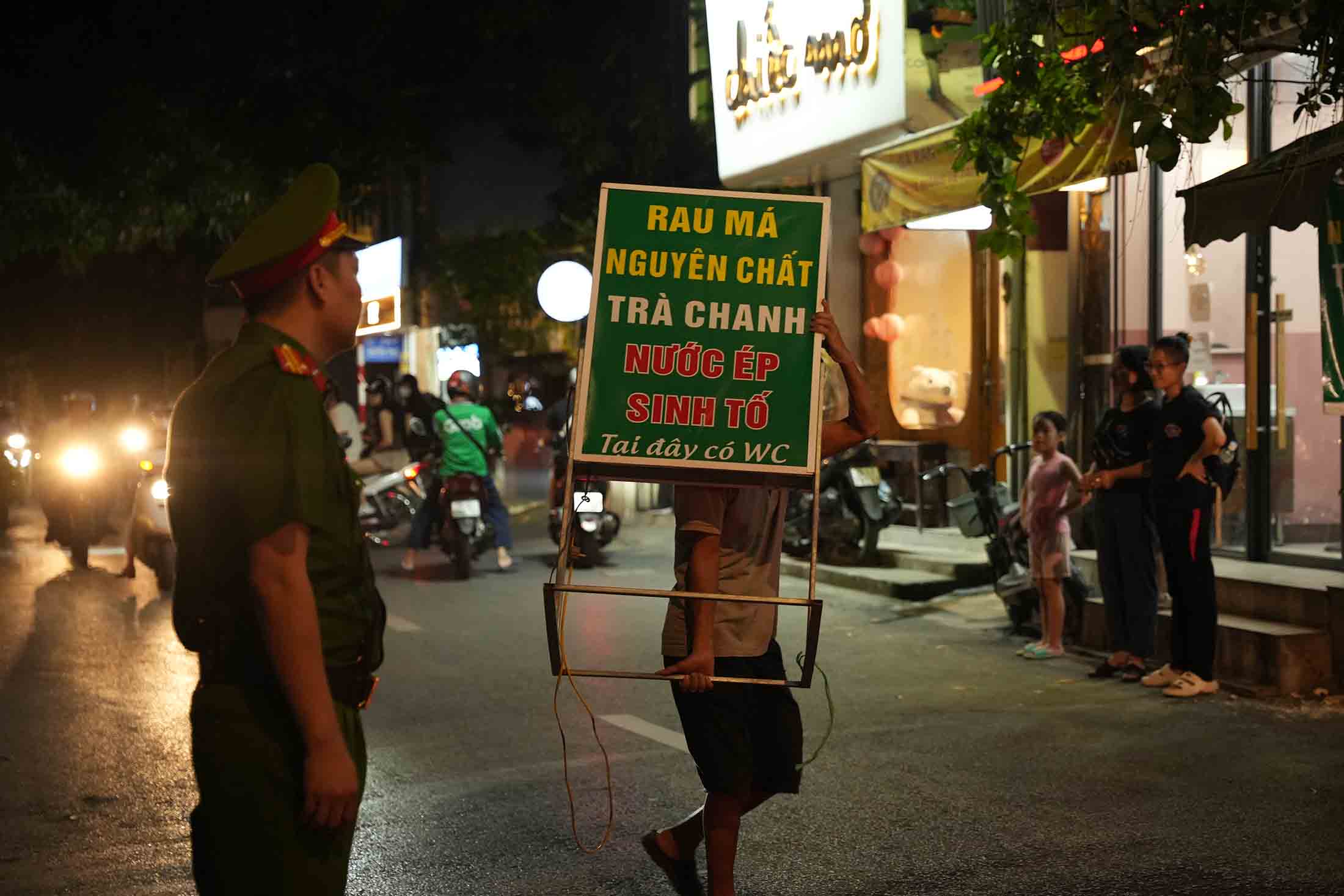 Lực lượng chức năng yêu cầu các hộ kinh doanh vật dụng lấn chiếm lòng đường, vỉa hè trên phố Mai Anh Tuấn. Ảnh: Hữu Chánh