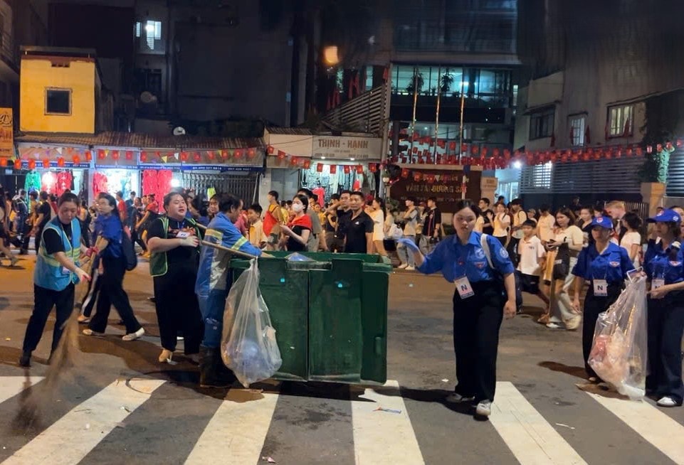 Kết thúc hợp luyện diễu, công nhân môi trường và sinh viên tình nguyện lại phối hợp thu gom rác, quét dọn đường phố. Ảnh: Thanh Loan