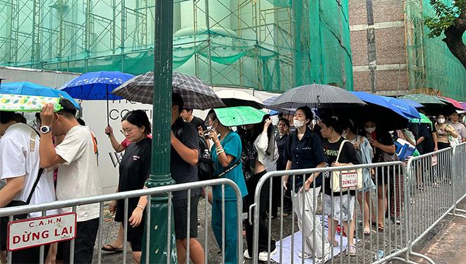 Cơn mưa rào bất chợt không làm nản lòng khán giả chờ lấy vé. Ảnh: Quỳnh An