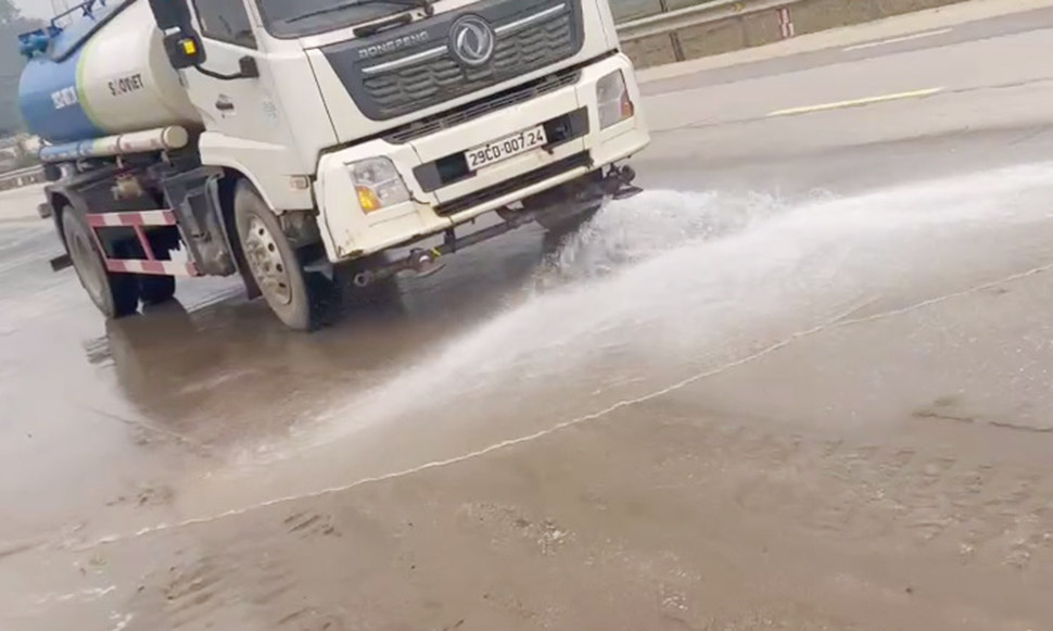 Xe bồn tưới nước nhằm tẩy rửa cát vương vãi trên Quốc lộ 1. Ảnh: Lam Hồng.