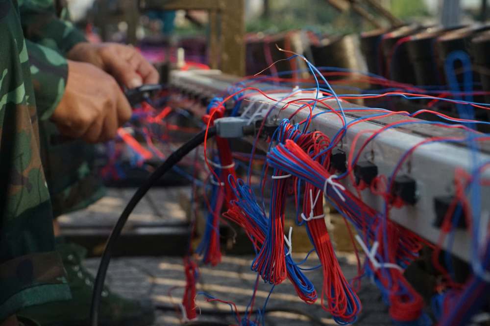 Sau khi cho pháo tầm cao vào ống, những dây mồi lửa điện được đấu nối với thanh điều khiển. Công việc này là một trong những khâu cuối cùng khi lắp pháo hoa. Ảnh: Anh Tú